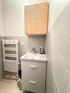 a bathroom with a white sink and a wooden cabinet at Hotel Le Chamonix in Chamonix