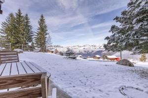 a snow covered yard with a bench and trees at Schwabhorn in Axalp