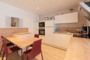 a kitchen with white cabinets and a wooden table at Libellule - Proche plage - Terrasse in Pornichet +6 photos