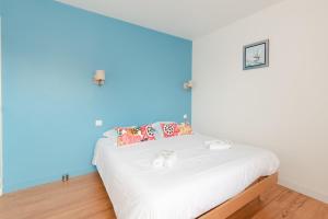 a bedroom with a white bed with a blue wall at Libellule - Proche plage - Terrasse in Pornichet