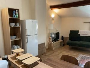 a kitchen with a refrigerator and a table and a couch at Parenthèse clunysoise in Cluny