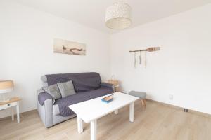 a living room with a couch and a table at Libellule - Proche plage - Terrasse in Pornichet