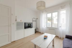 a white living room with a couch and a table at Libellule - Proche plage - Terrasse in Pornichet
