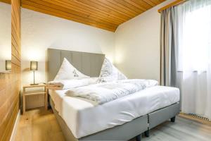 a bedroom with a bed with white sheets and a window at First Apartment - Aare Jungfrau AG in Grindelwald