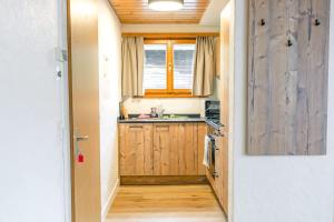 a small kitchen with wooden cabinets and a window at First Apartment - Aare Jungfrau AG in Grindelwald
