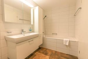 a white bathroom with a sink and a bath tub at Schilthorn Apartment - Aare Jungfrau AG in Wilderswil