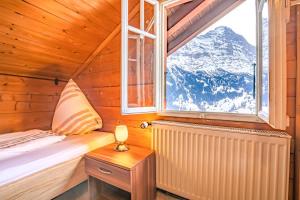 una stanza con un letto e una finestra con una montagna innevata di Chalet Weid - Aare Jungfrau AG a Grindelwald