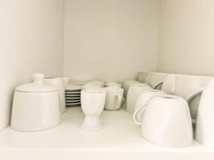 a group of white cups and plates on a shelf at Nika Apartment - Aare Jungfrau AG in Grindelwald