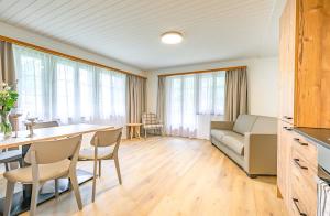 a living room with a table and chairs and a couch at Lauberhorn Apartment - Aare Jungfrau AG in Grindelwald