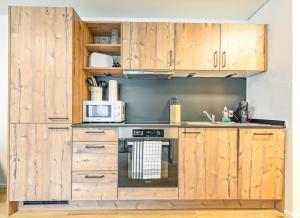 a kitchen with wooden cabinets and a stove at Lauberhorn Apartment - Aare Jungfrau AG in Grindelwald