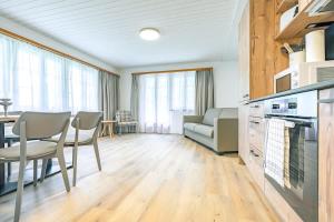a kitchen and living room with a table and chairs at Lauberhorn Apartment - Aare Jungfrau AG in Grindelwald