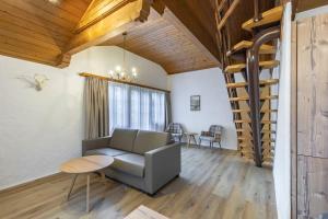 a living room with a couch and a spiral staircase at Apartment Eiger - Aare Jungfrau AG in Grindelwald