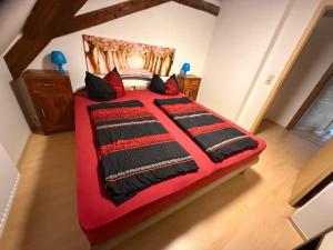 a bedroom with a red bed with black and red pillows at stilvolle Dachgeschoss-Wohnung in Top-Lage in Großröhrsdorf
