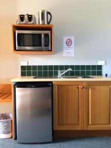 a kitchen with a stainless steel refrigerator and a microwave at Cannon Park Motel in Cairns