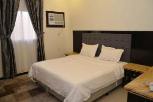 a bedroom with a bed with white sheets and a window at فخامة الديار للشقق المخدومة Fakhamat Aldyar For Serviced Apartments in Taif