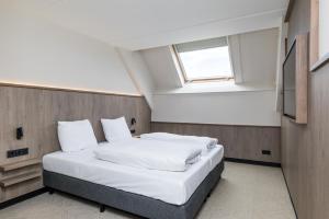 a bedroom with a bed with white sheets and a window at Alpine Hotel by SnowWorld in Landgraaf