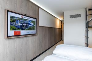 a bedroom with a flat screen tv on a wall at Alpine Hotel by SnowWorld in Landgraaf
