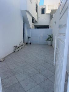 an empty courtyard with a white fence and potted plants at Cozy Corner in Sousse