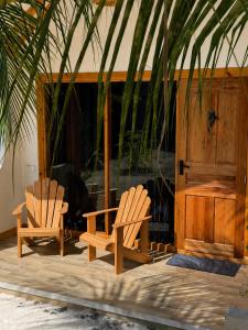 two wooden chairs sitting in front of a building at Black Pearl View in Himandhoo 