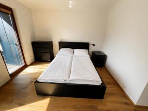 a bedroom with a bed with white sheets and a window at Apartmán Lidická bouda in Pec pod Sněžkou