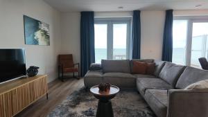 a living room with a couch and a television at Residentie De Zeester | 4 Pers. De Zeester in Scherpenisse