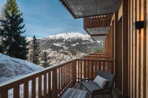 a balcony with a chair and a snow covered mountain at Guernerés & Spa by Alpine Resorts in Grimentz