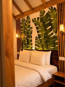 a bedroom with a bed with a painting of leaves at Black Pearl View in Himandhoo 
