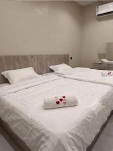 a white bed with a white towel with roses on it at Hail View شقق فيو حائل المخدومة in Hail
