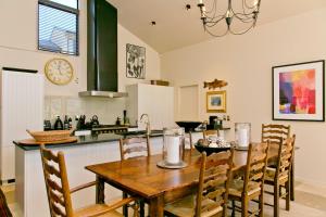 cocina y comedor con mesa de madera y sillas en The Point Villas, en Taupo