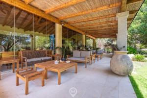 a patio with tables and chairs and a wooden ceiling at Estay - Tanca de Mar in Maracalagonis
