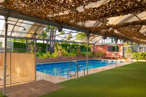 a swimming pool in a building with a greenhouse at Kampaoh Estepona in Estepona