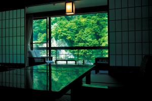 a room with a glass table and a large window at Enraku in Kurobe