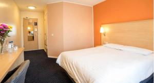 a hotel room with a large white bed and flowers at Cosy Inn in Mirfield