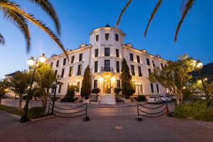 a large white building with palm trees in front of it at Thermae Sylla Spa & Wellness Hotel in Loutra Edipsou