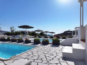 a swimming pool with umbrellas and the ocean in the background at Katharos Pool Villas in Oia