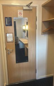 a door in a room with a mirror and a bathroom at Cosy Inn in Mirfield