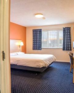 a hotel room with a bed and a window at Cosy Inn in Mirfield