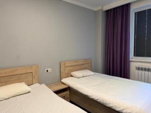 two twin beds in a room with a window at 名宿 395 Hostel in Bishkek +6 photos