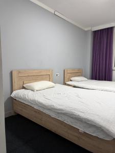 two beds in a room with white walls and purple curtains at 名宿 395 Hostel in Bishkek