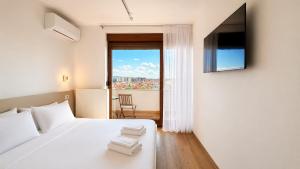 a bedroom with a white bed and a balcony at Makadam Hotel in Prizren