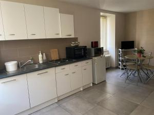 a kitchen with white cabinets and a sink and a table at Meublé lilas in Réaumur
