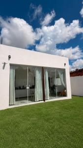 a white building with large windows and green grass at Chalé Arandu in Santo Amaro