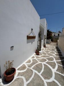 a white wall with potted plants and a sign on it at Bougainvillea in Asklipiḯon