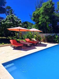 a group of chairs and umbrellas next to a swimming pool at Villa Orita in Nosy Be