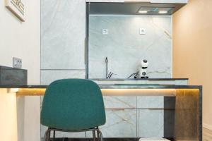 a bathroom with a sink and a green chair at Apartamentos El Real in Mota del Cuervo