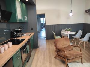 a kitchen with green cabinets and a table with a chair at Alte Schule Gästehaus - Klassenzimmer Loft in Bitburg