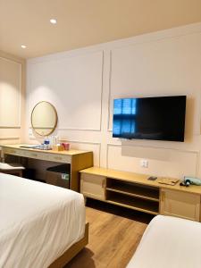 a hotel room with a bed and a flat screen tv at Peace Home Boutique Hotel in Phan Thiet