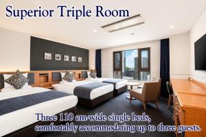 a hotel room with three beds and a television at ART HOTEL Sasebo Central in Sasebo