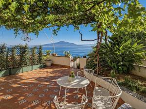 a table and chairs on a patio with a view of the ocean at Maison La Torretta in Vico Equense