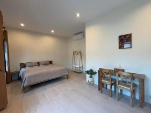 a bedroom with a bed and a table and a chair at Langbaan cafe and homestay in Ban Mai